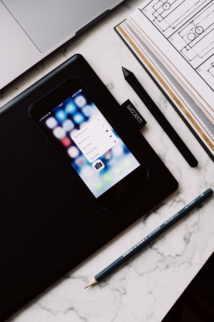 From above of cellphone screen with pop up window and open book with draft and pen located on marble table